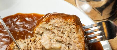 A meatloaf with gravy on a white plate.