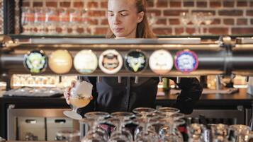 A barista preparing a drink behind a tap with various beer options.