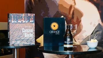 Un livre intitulé « Carnaval de Binche » et une bouteille de vin de Binche sont posés sur une table, à côté d’un verre et d’un bol de fromage.