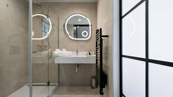 Un baño moderno con ducha envuelta en vidrio, un lavamanos con espejo y un perchero para toallas.
