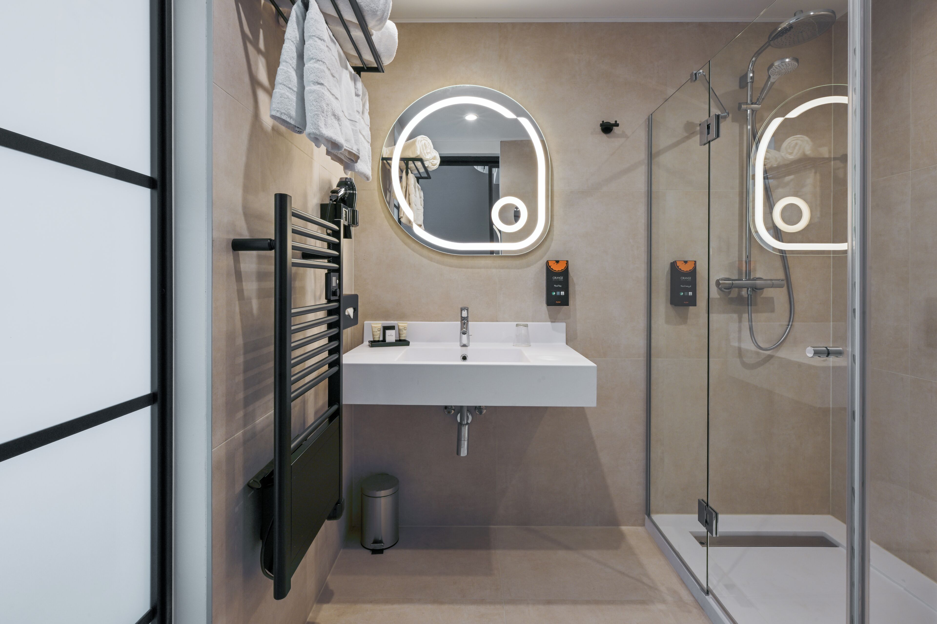Ein modernes Badezimmer mit Duschkabine aus Glas, einem weißen Waschbecken und einem Handtuchhalter.