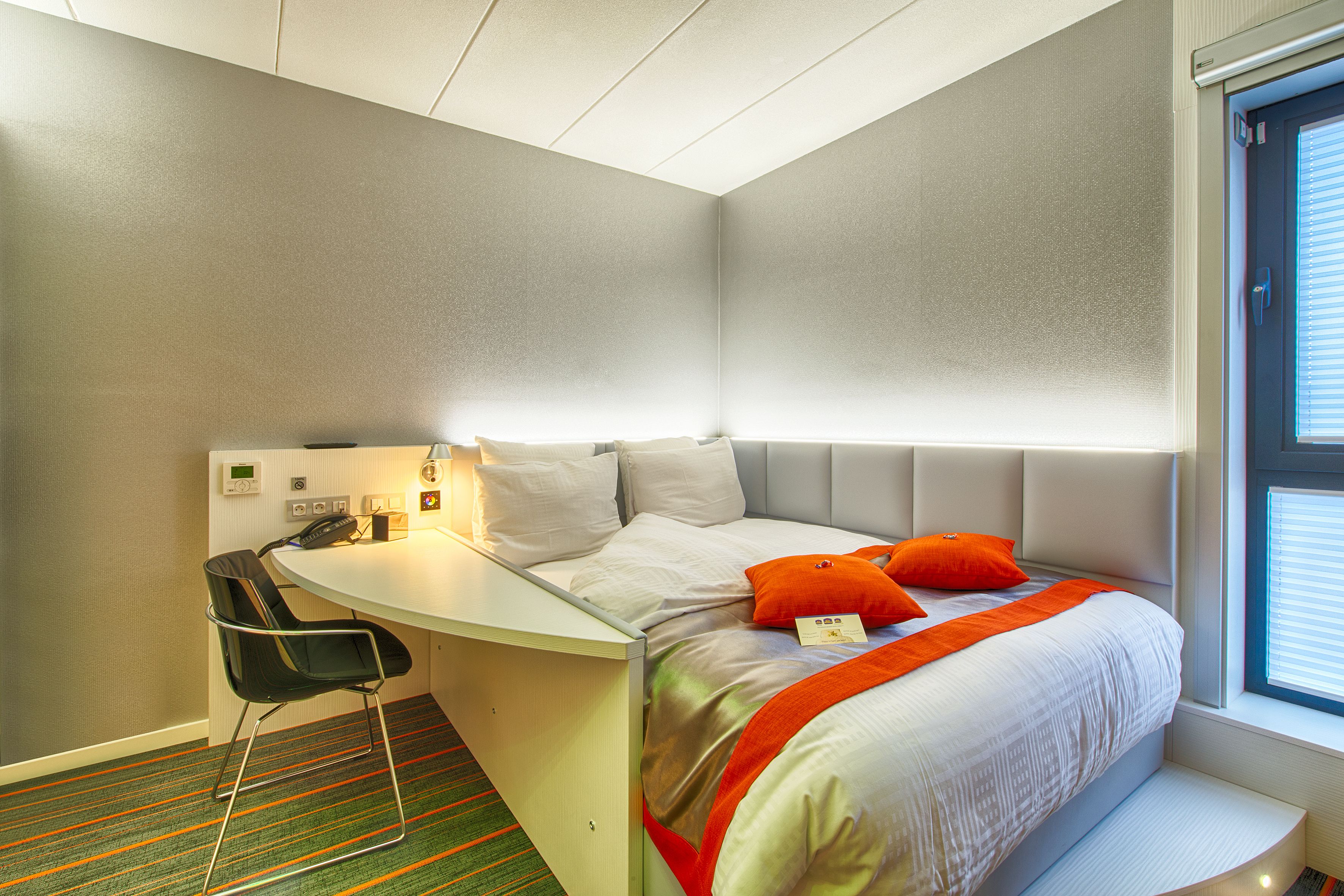 Een hotelkamer met een bed, een bureau en een stoel.