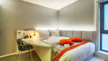 Een hotelkamer met een bed, een bureau en een stoel.