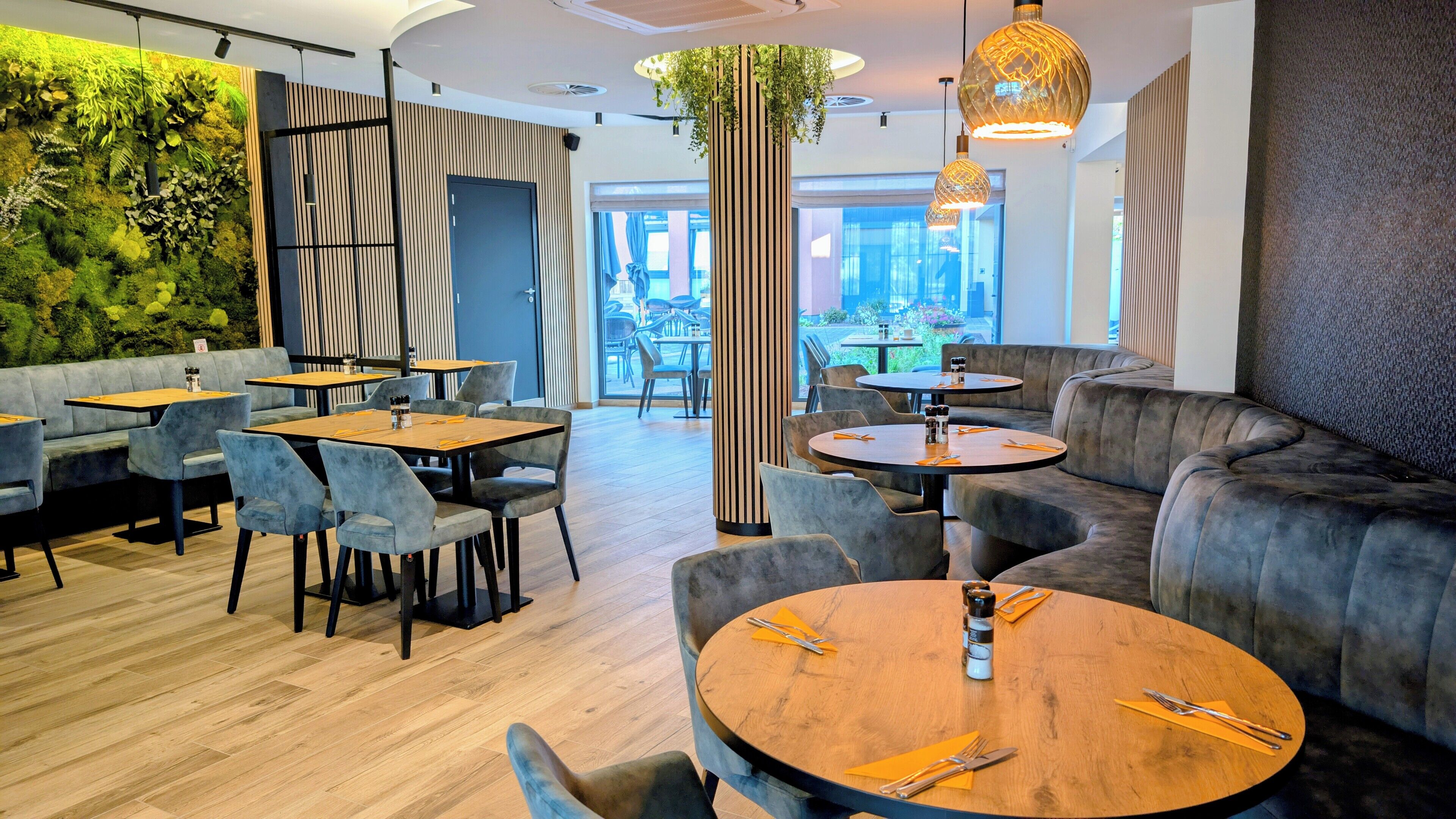 A modern restaurant with wooden tables and grey upholstered seating.