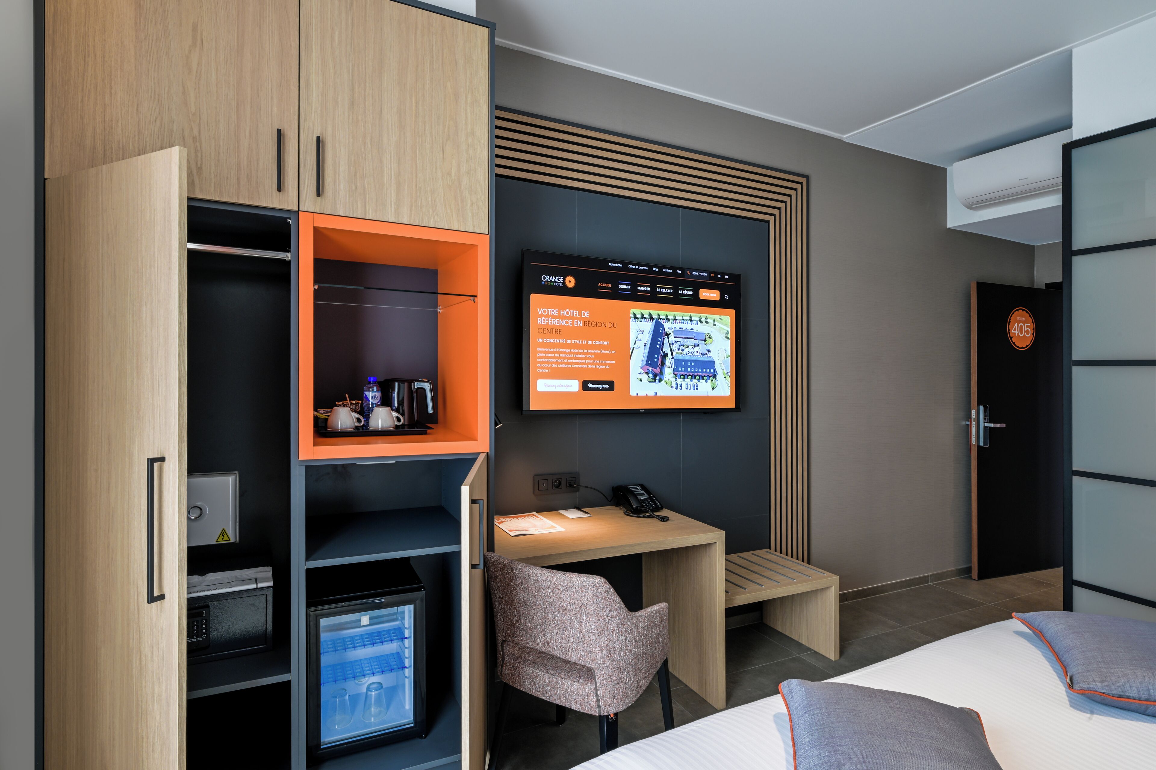 Ein Hotelzimmer mit Bett, Schreibtisch, Stuhl, Kleiderschrank und einem Fernseher, der eine Hotellagekarte zeigt.