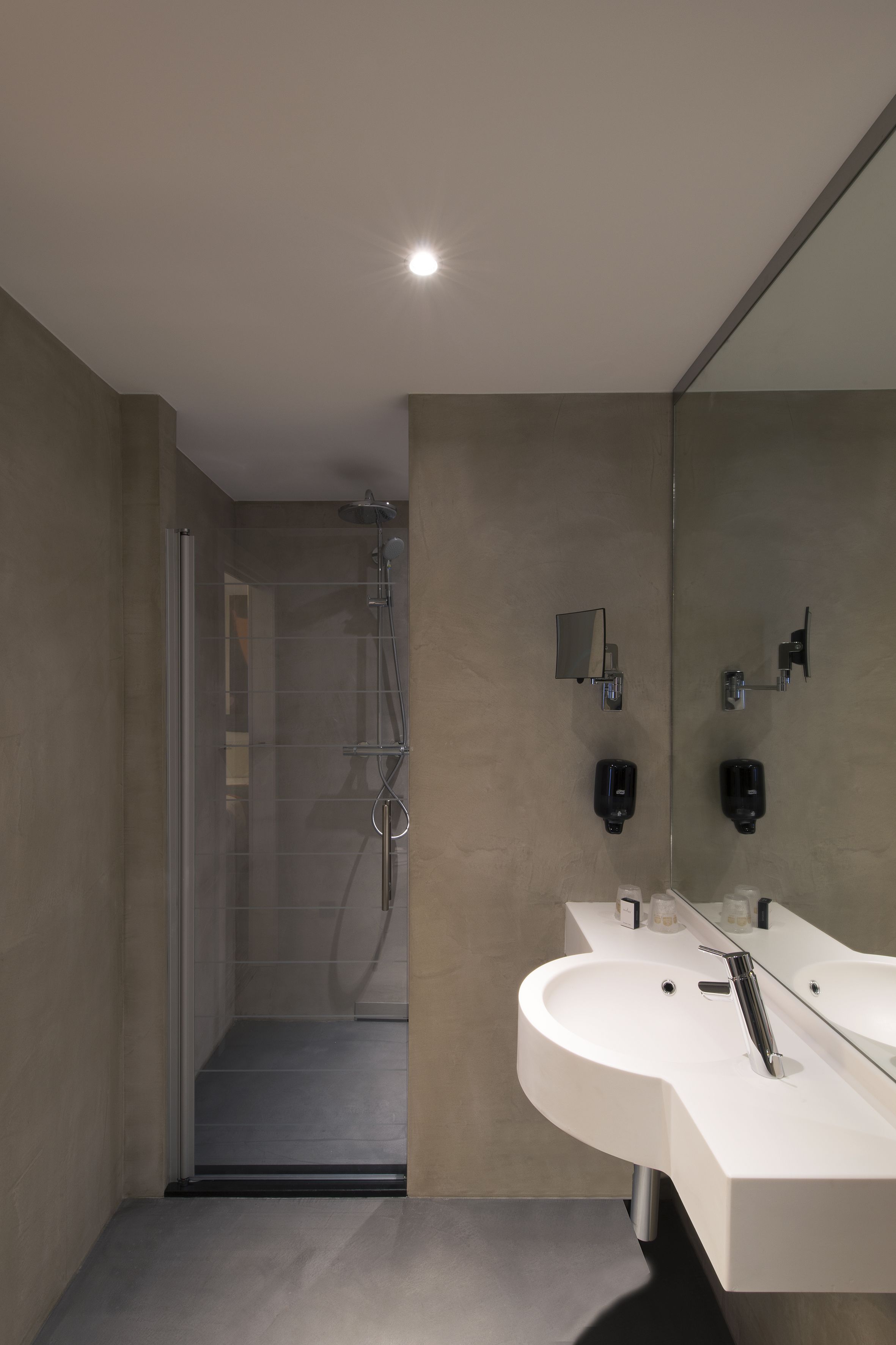 A modern bathroom with a glass shower enclosure, a white sink with a mirror, and a wall-mounted towel rack.