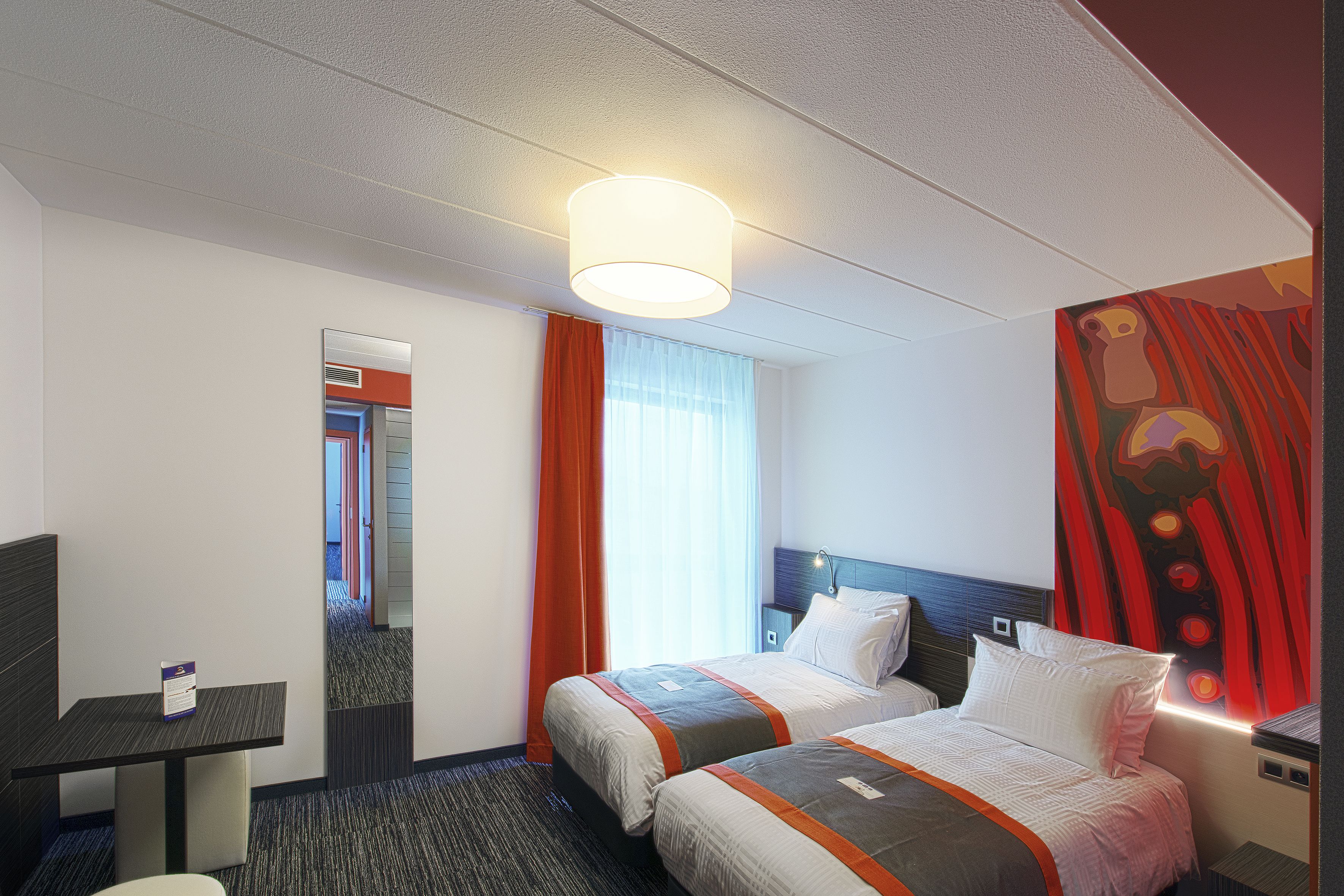Habitación de hotel con dos camas, un escritorio, un espejo y un cuadro en la pared.