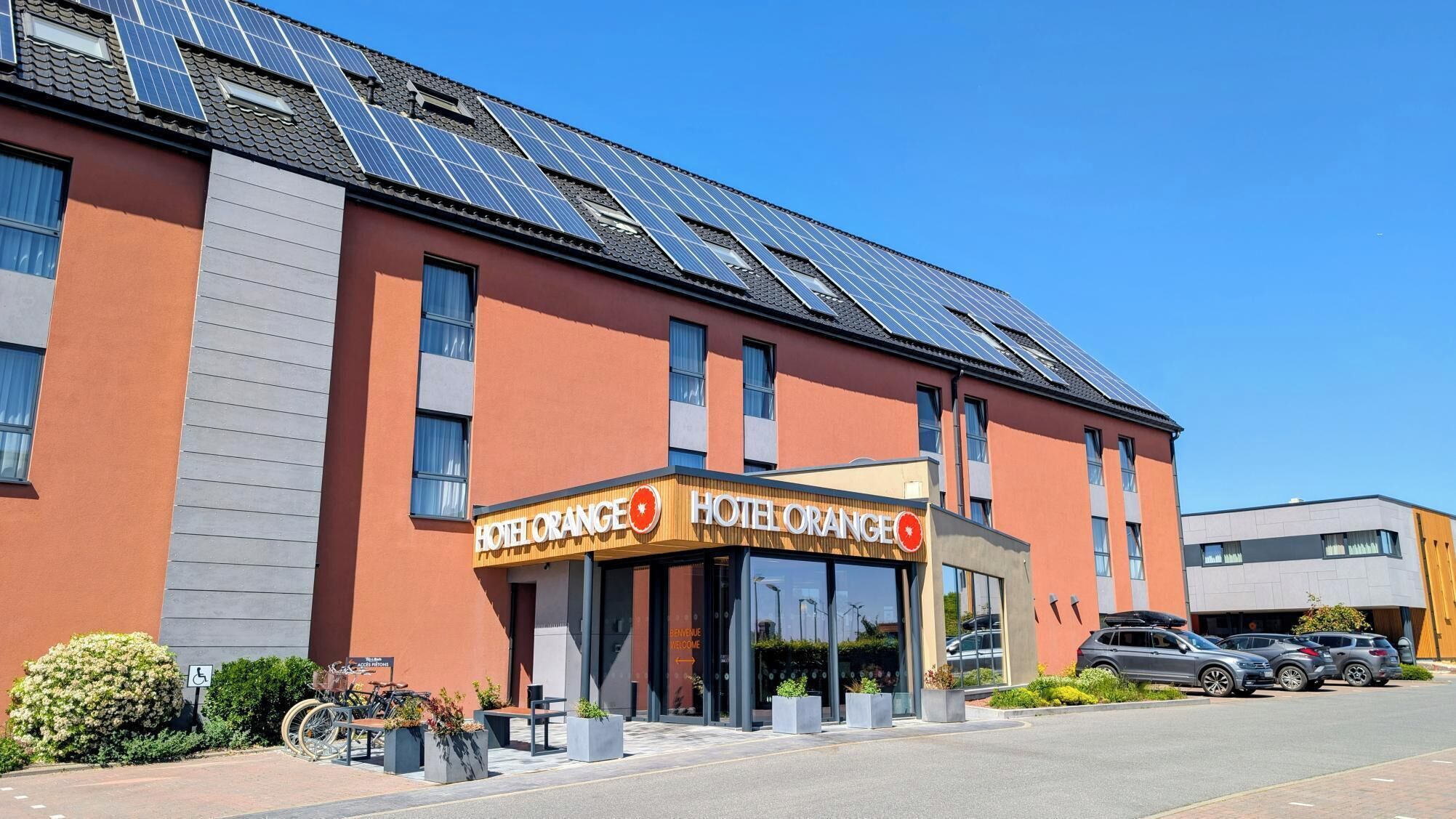Ein Hotel mit modernem Design, Solaranlage auf dem Dach und einladendem Eingang.
