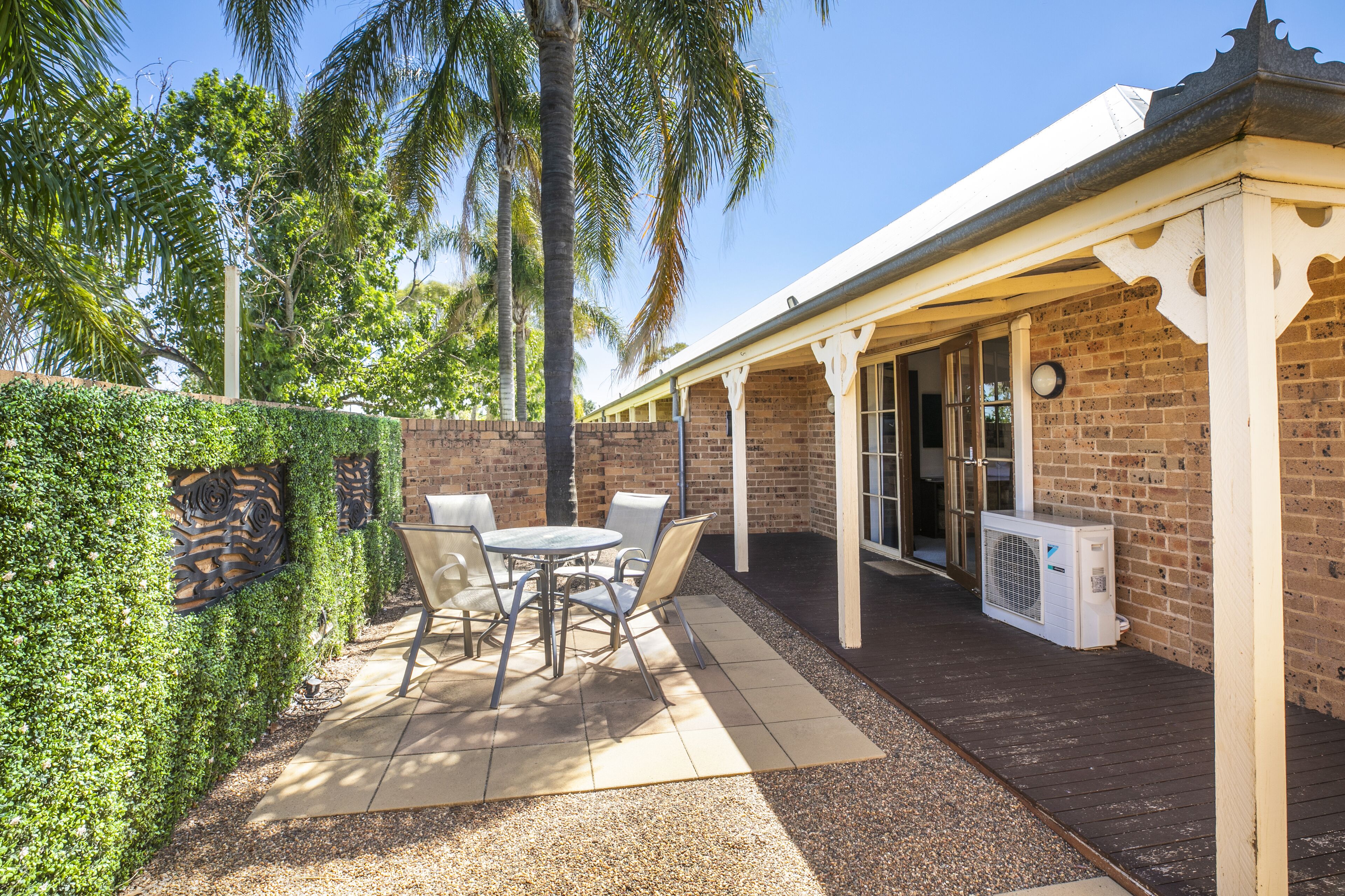A patio area with a table and chairs, a brick wall, and an air conditioning unit.