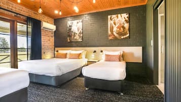 Een hotelkamer met twee bedden, een bakstenen muur en kunstwerken.