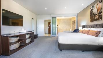 A modern bedroom with a large bed, a vanity with a mirror, and a walk-in closet.