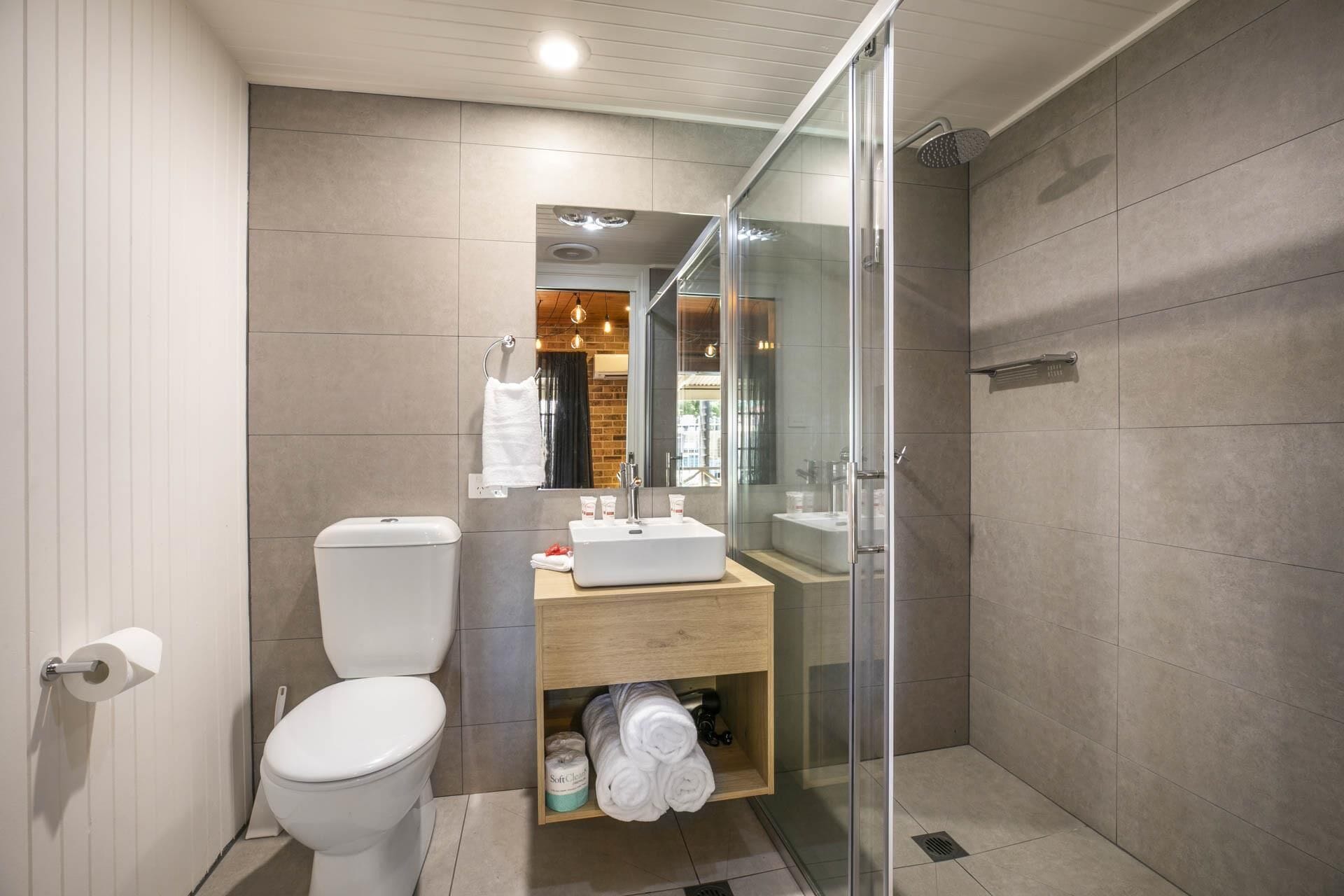 Un baño moderno con inodoro, lavamanos y ducha.