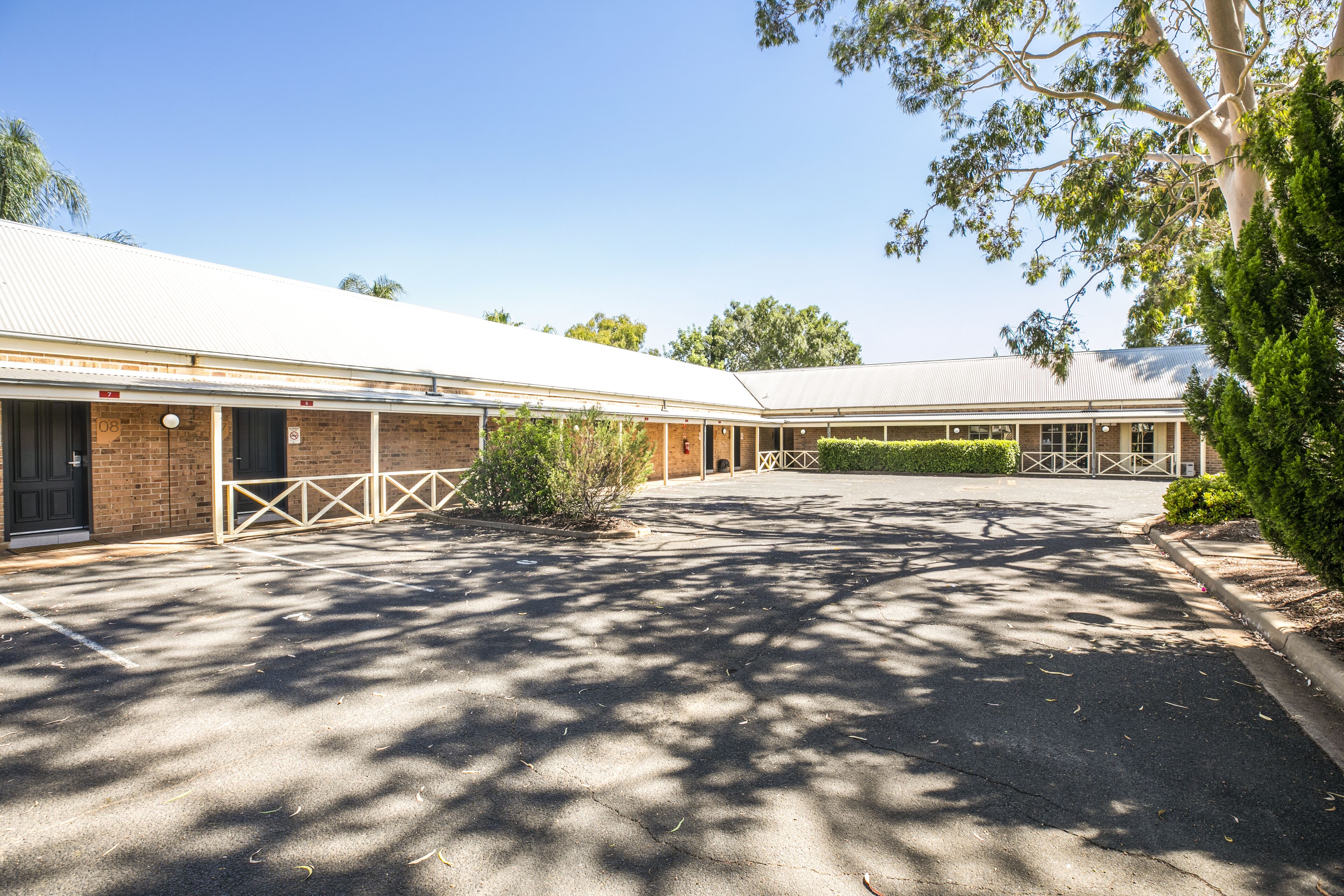A building with a covered parking area and a small garden.