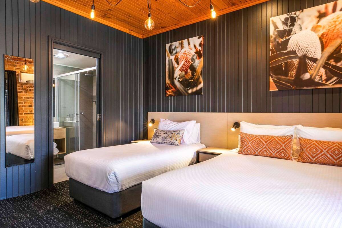 A hotel room with two beds, a large mirror, and artwork on the walls.