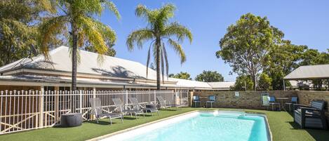 Ein Pool mit Liegestühlen und Palmen.