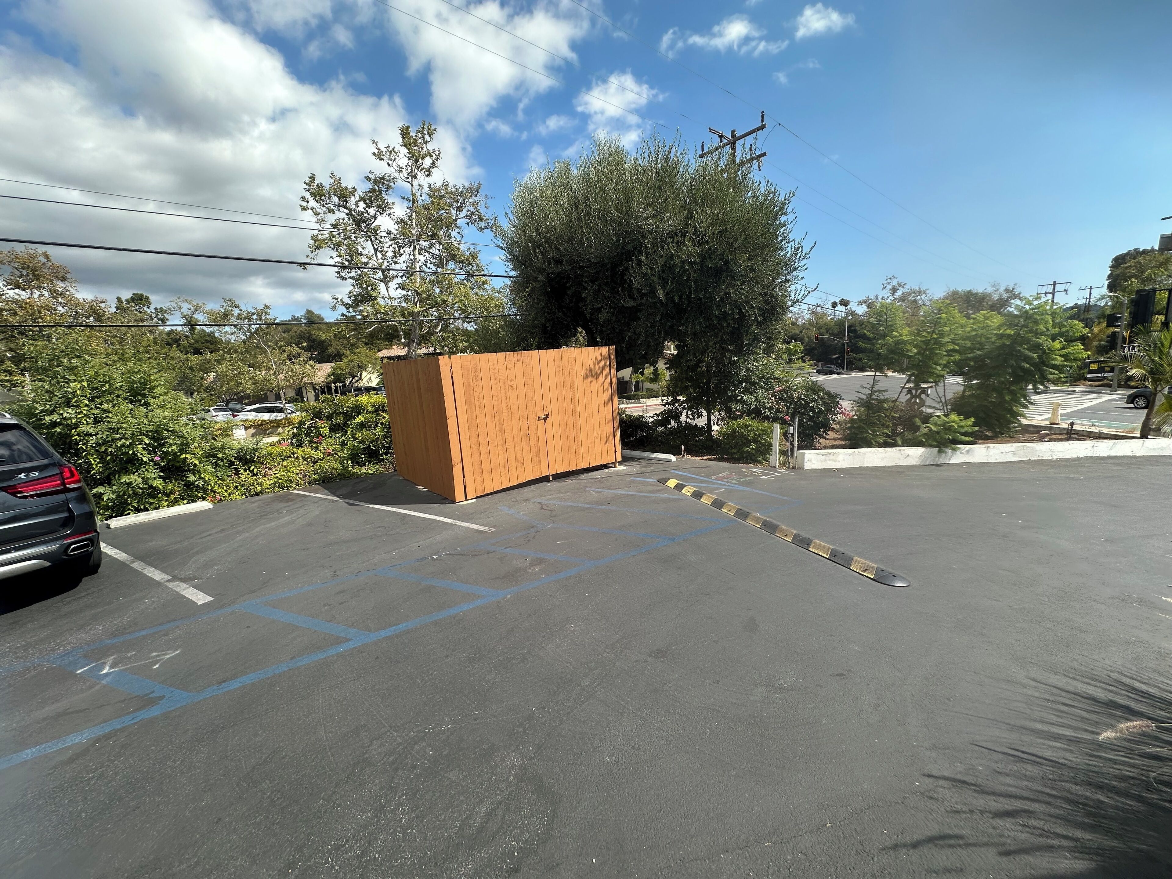 A parking lot with a wooden structure, trees, and a clear sky.