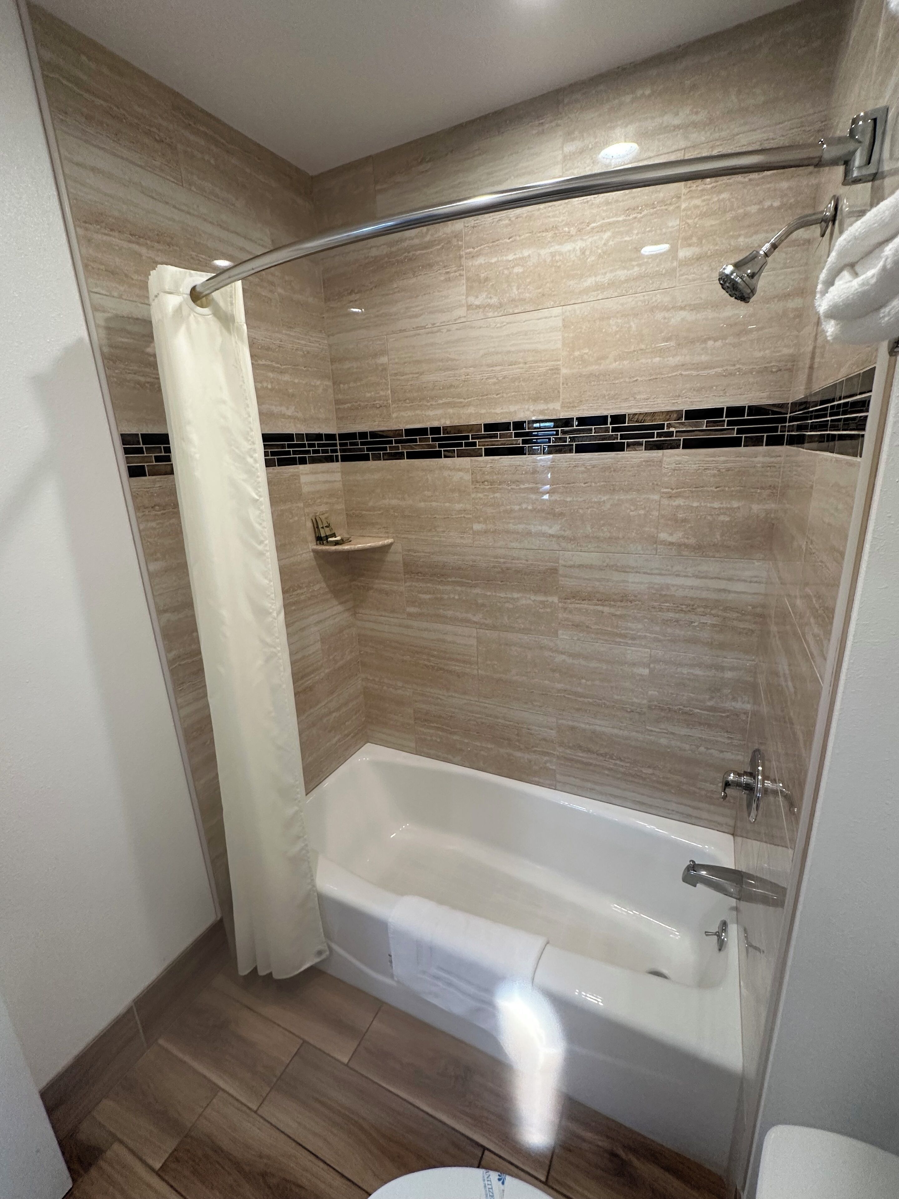 A modern bathroom with a bathtub, shower, and a towel rack.