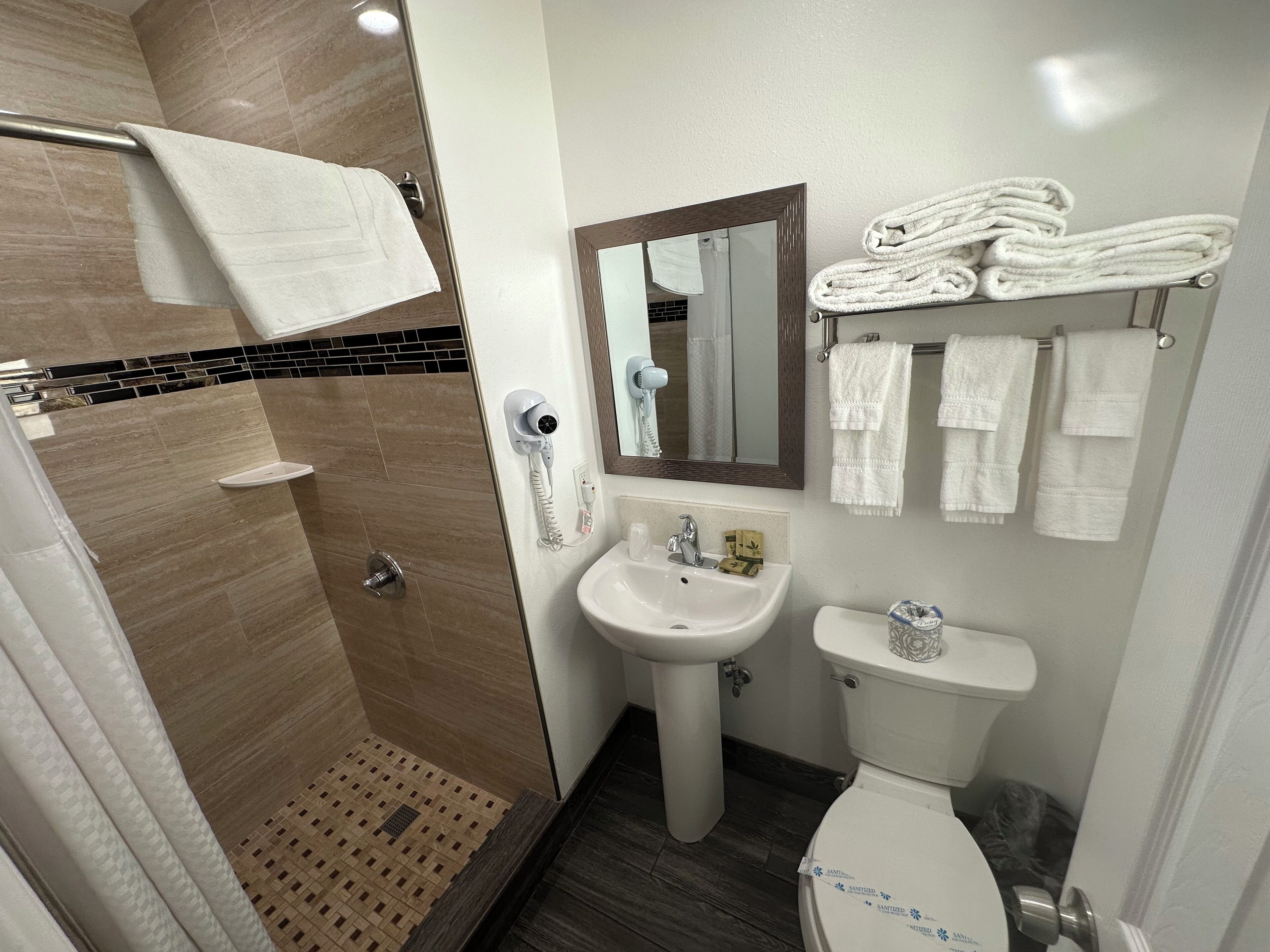 A bathroom with a shower, sink, toilet, and towel rack.
