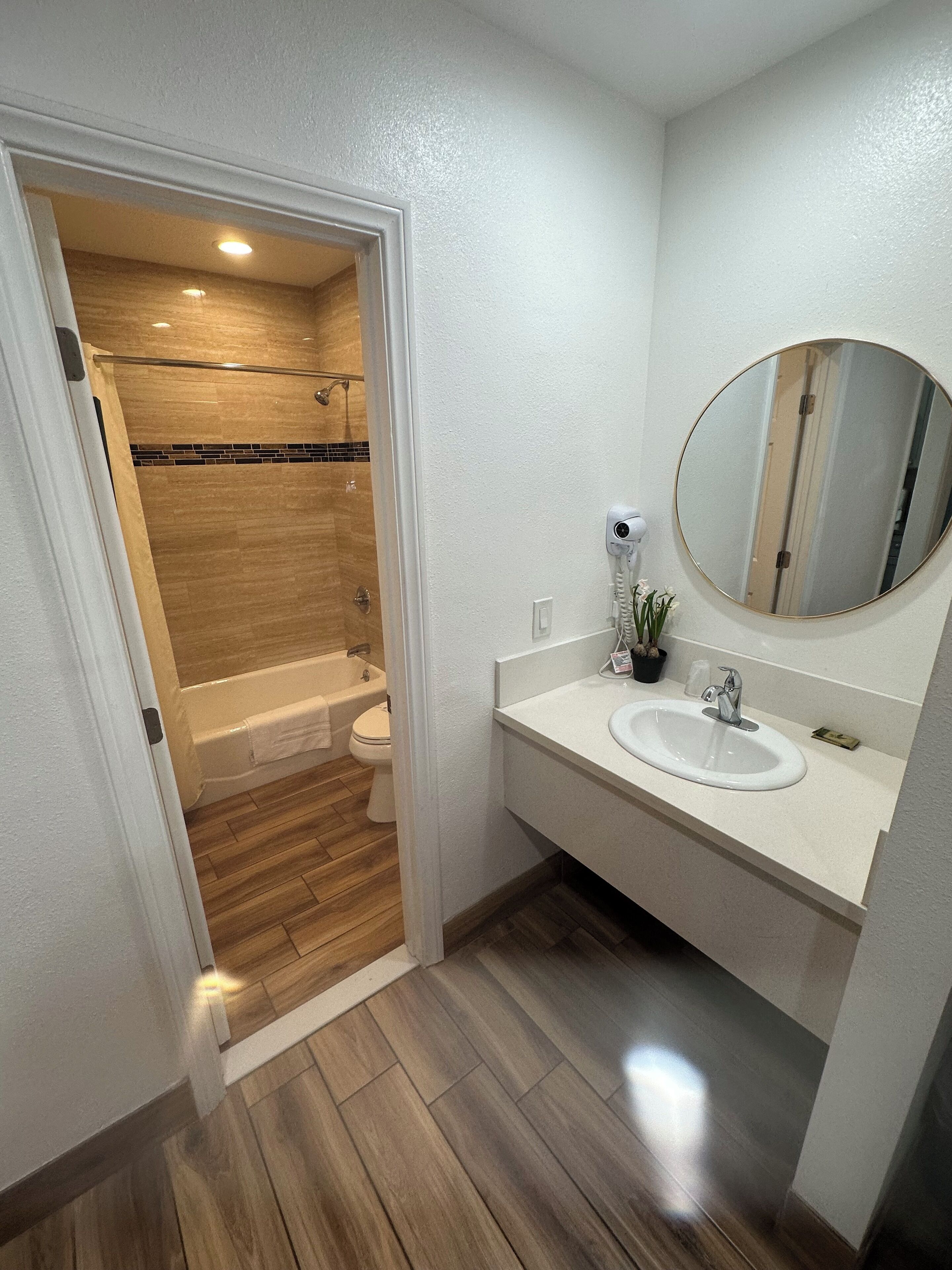 Une salle de bain moderne avec une douche en bois, un lavabo blanc et un grand miroir.