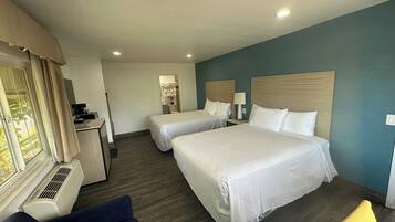 A hotel room with two beds, a desk, a chair, and a window with curtains.