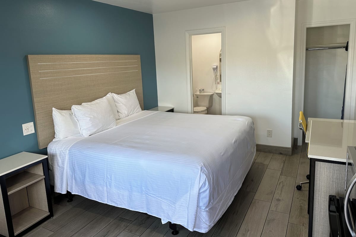 A hotel room with a large bed, bedside tables, a mirror, and a small bathroom.