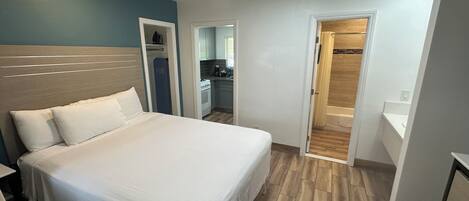 A bedroom with a bed, a wardrobe, and a bathroom visible through an open door.