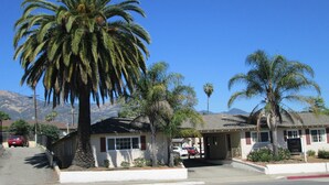 A two-story building with a red car parked in front.