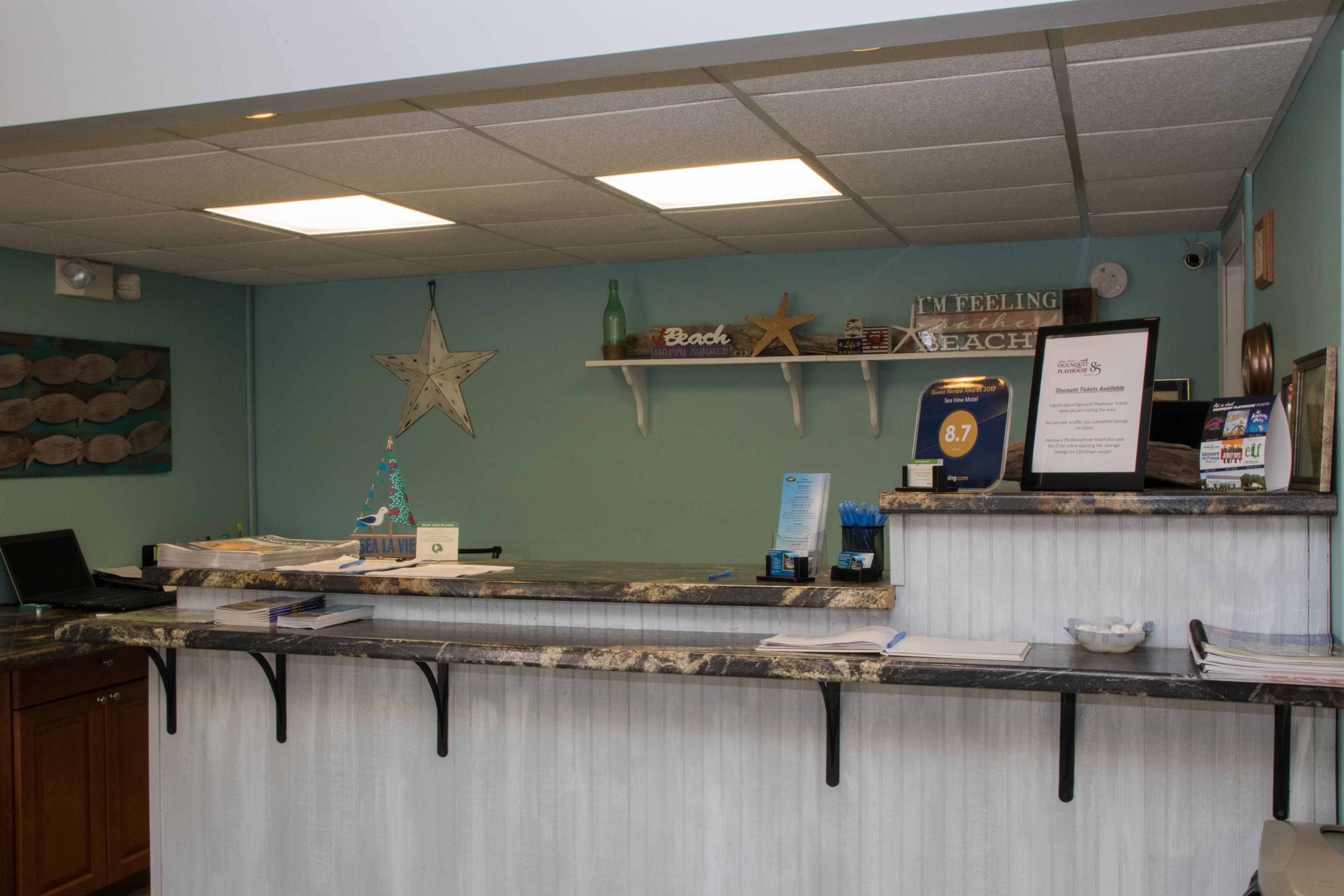 Un mostrador de recepción con una computadora, un adorno con forma de estrella y una repisa con una estrella de mar y un letrero que dice "Beach".