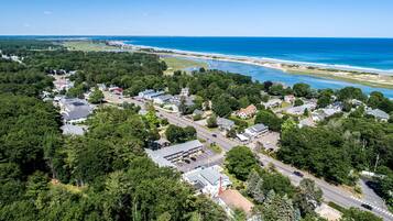 Vue aérienne d’une zone résidentielle côtière, avec des maisons, des routes et une plage.
