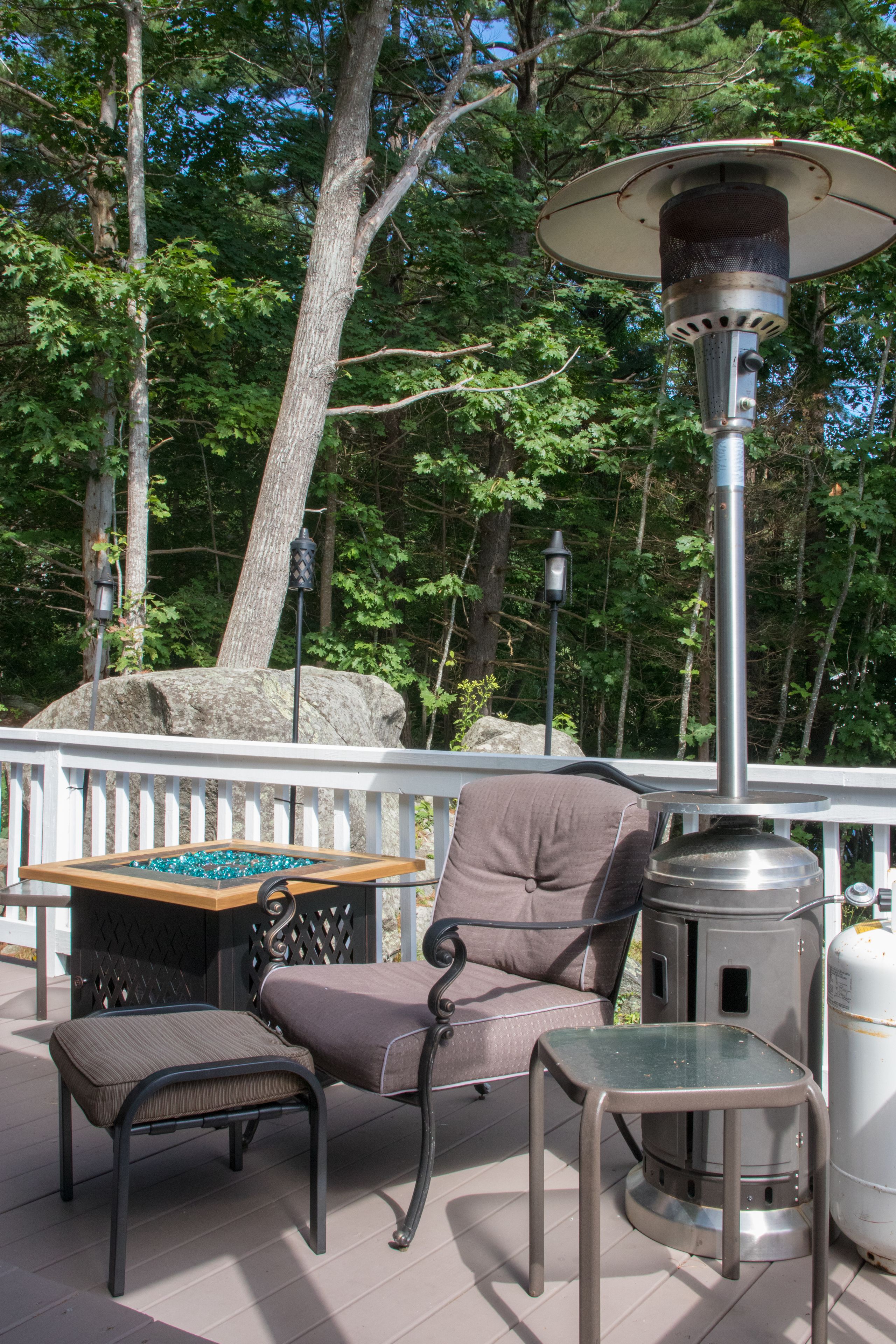 A deck with a chair, table, and a portable heater.