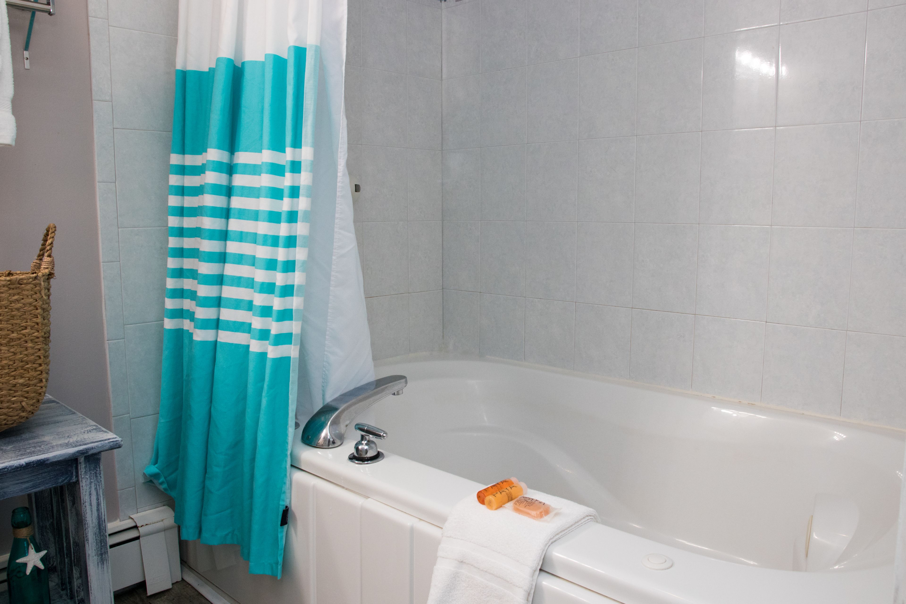 A bathroom with a bathtub, a shower curtain, and a towel rack.