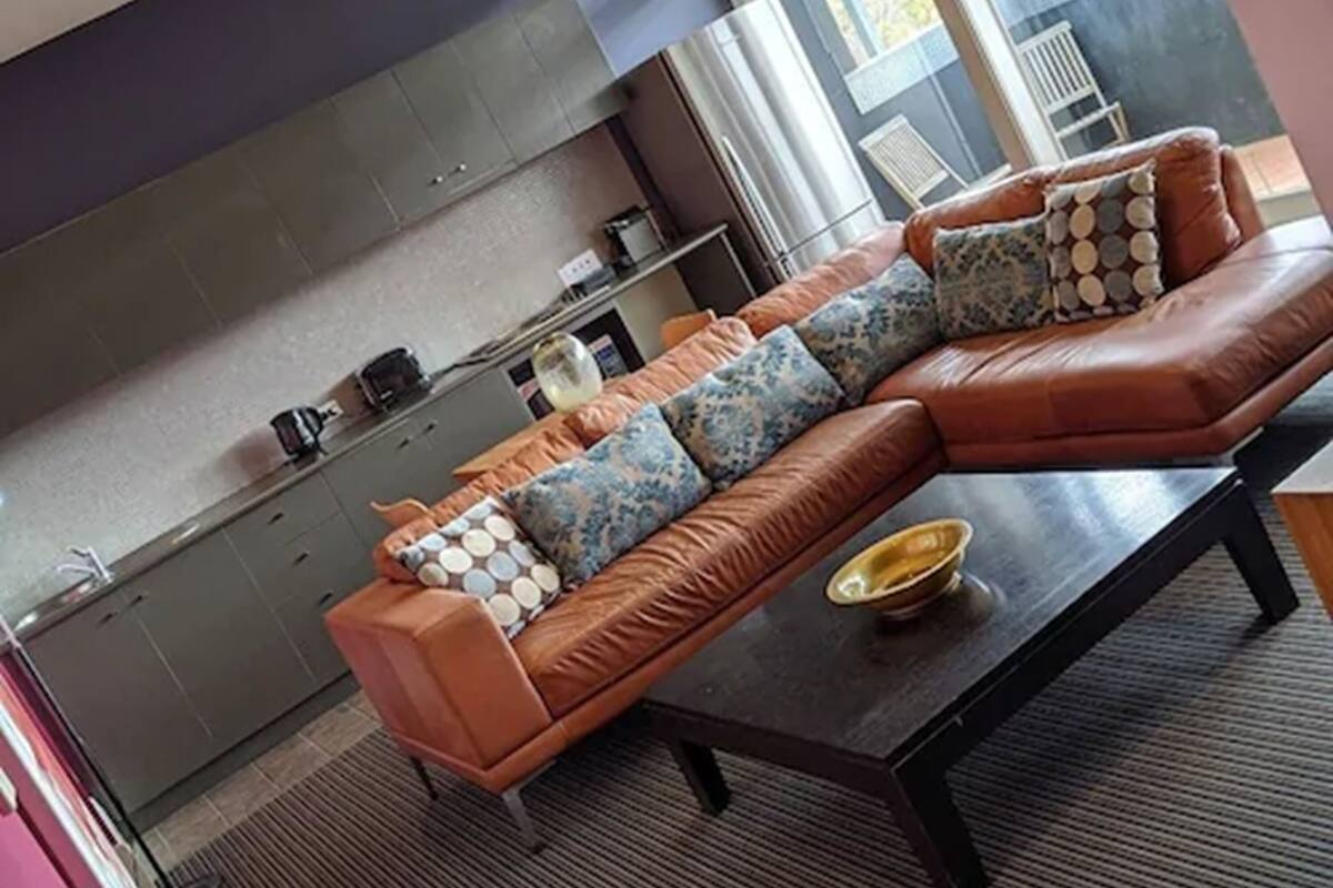 A modern living room with a brown leather sofa, patterned cushions, and a coffee table.