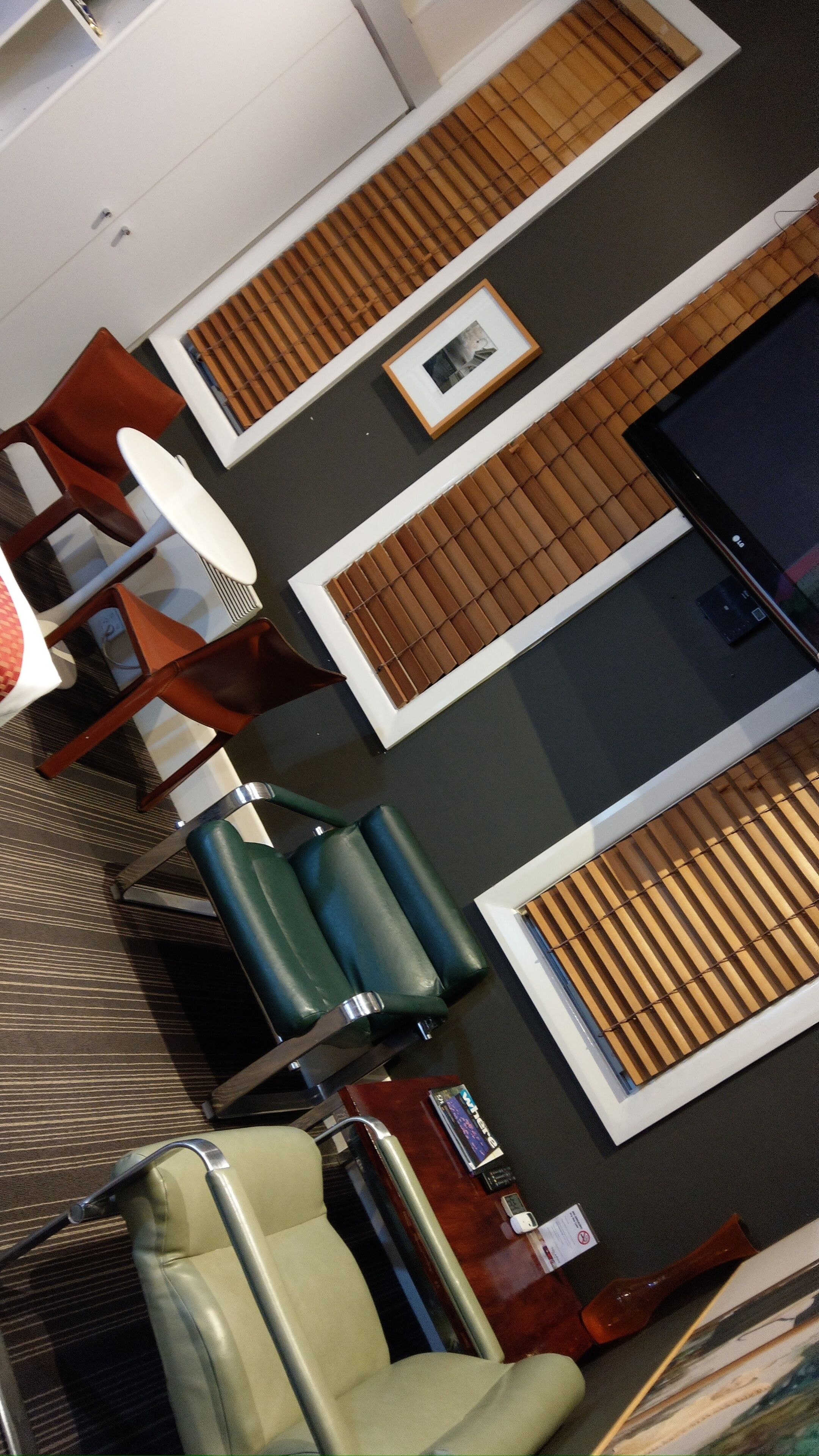 A hotel room with a bed, a desk, a chair, a TV, and a window with blinds.