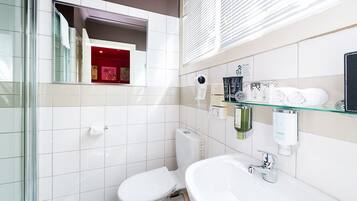 Un bany modern amb un espai de dutxa de vidre, un vàter blanc, un lavabo de vidre i un mirall sobre el lavabo.