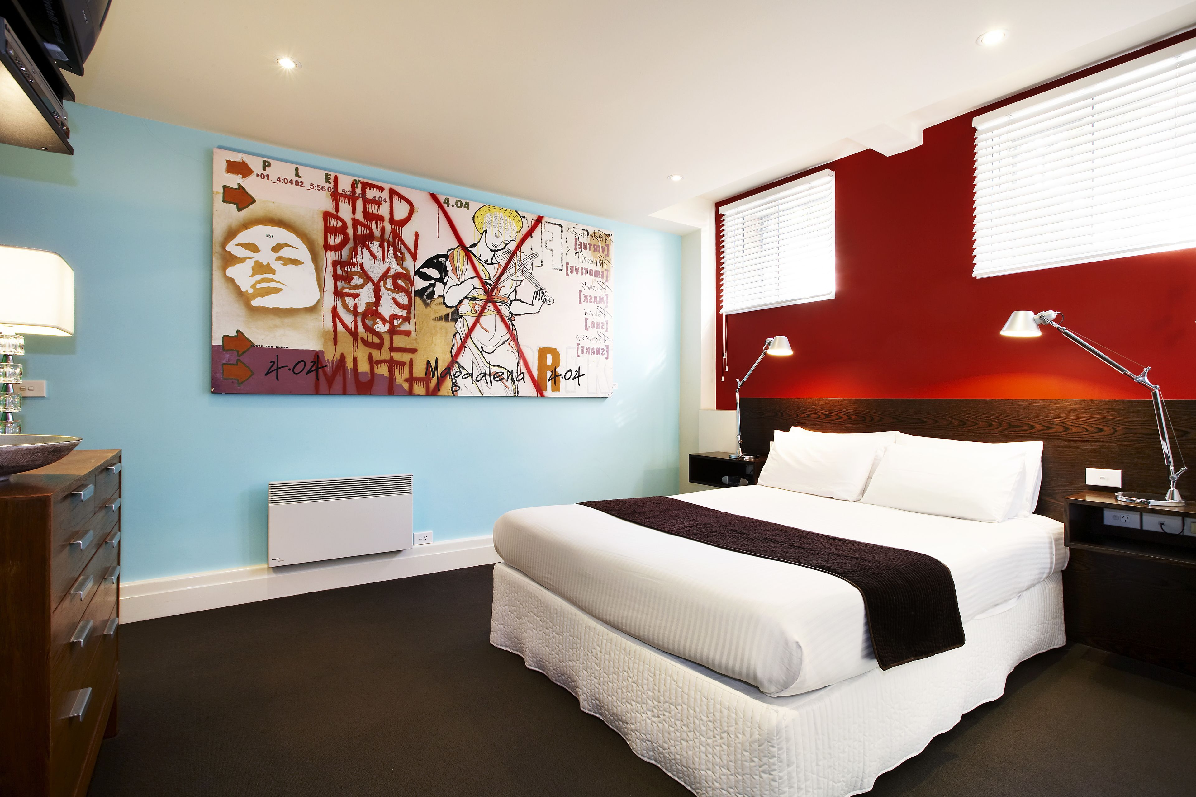 Un dormitorio moderno con una cama grande, una mesita de noche, una lámpara y una obra de arte en la pared.