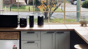 A kitchen with a window view, a microwave, a toaster, and a coffee maker on the counter. - Berrima Bakehouse Motel (Berrima)