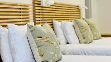 A hotel room with two beds, each with white bedding and decorative pillows.