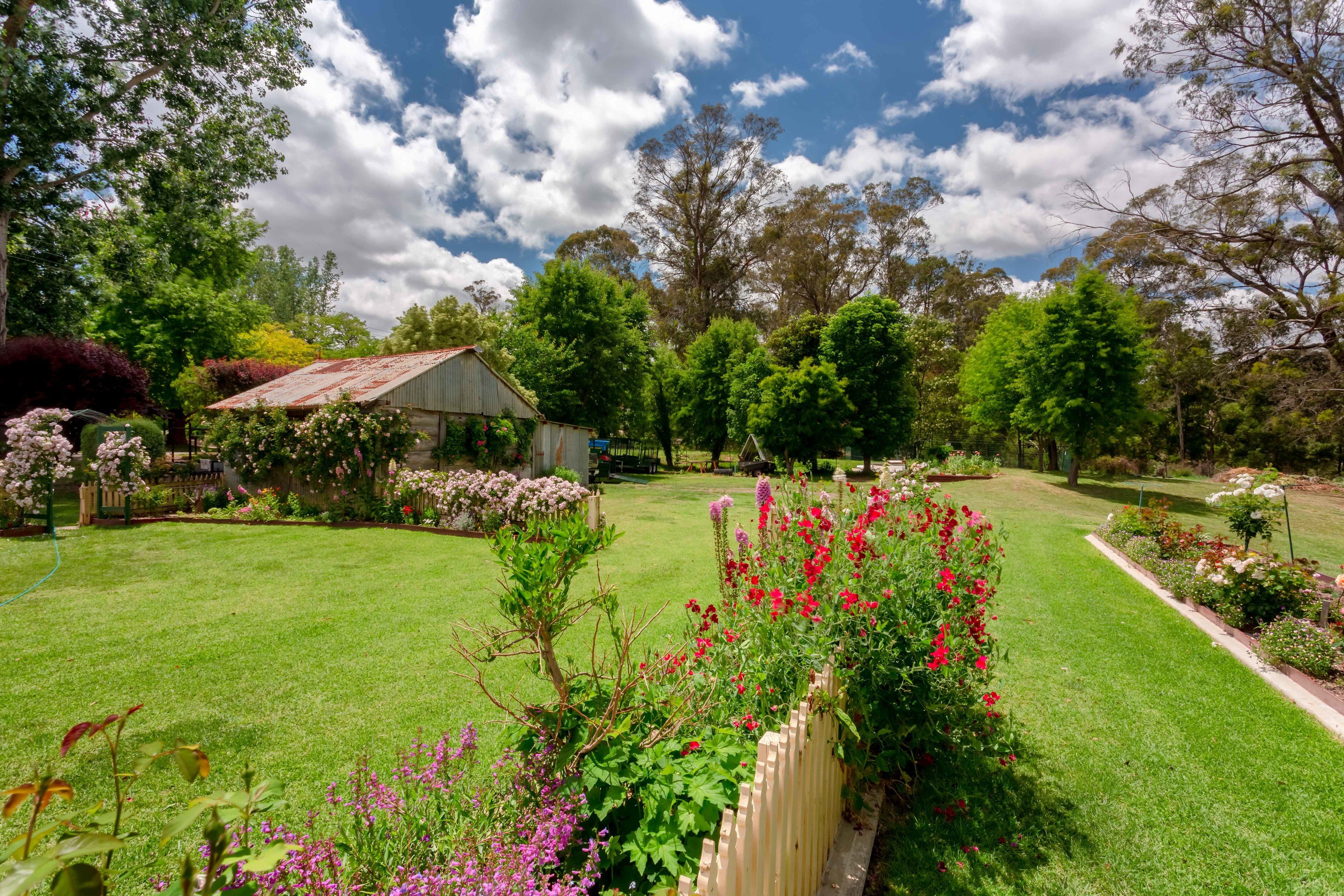 A well-maintained garden with a variety of flowering plants and a wooden fence.