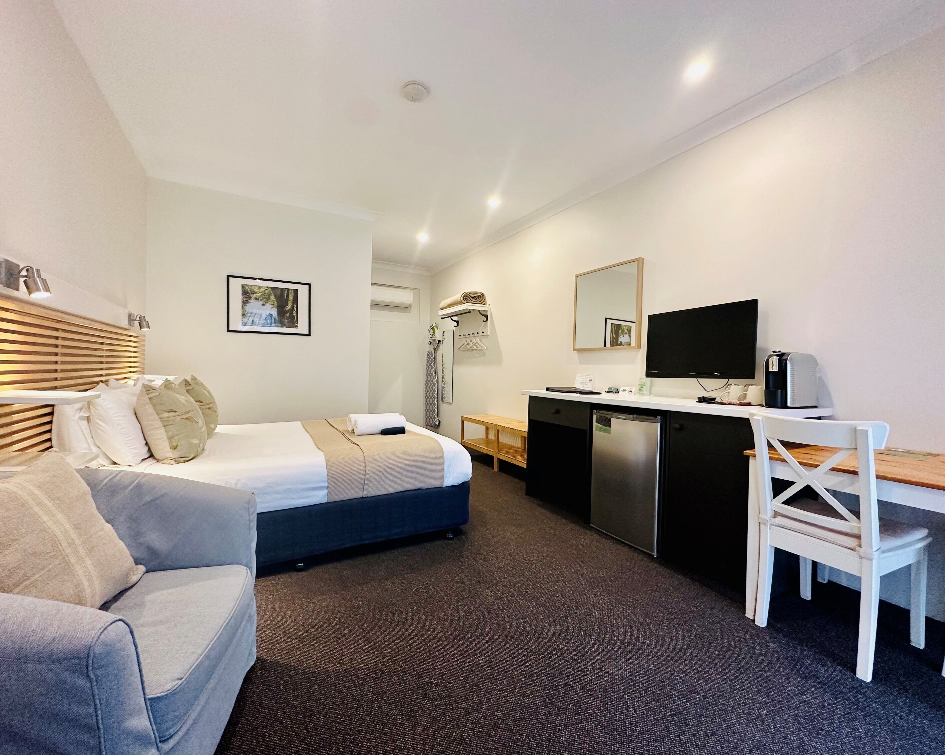 A hotel room with a bed, a desk, a chair, a television, and a coffee maker.