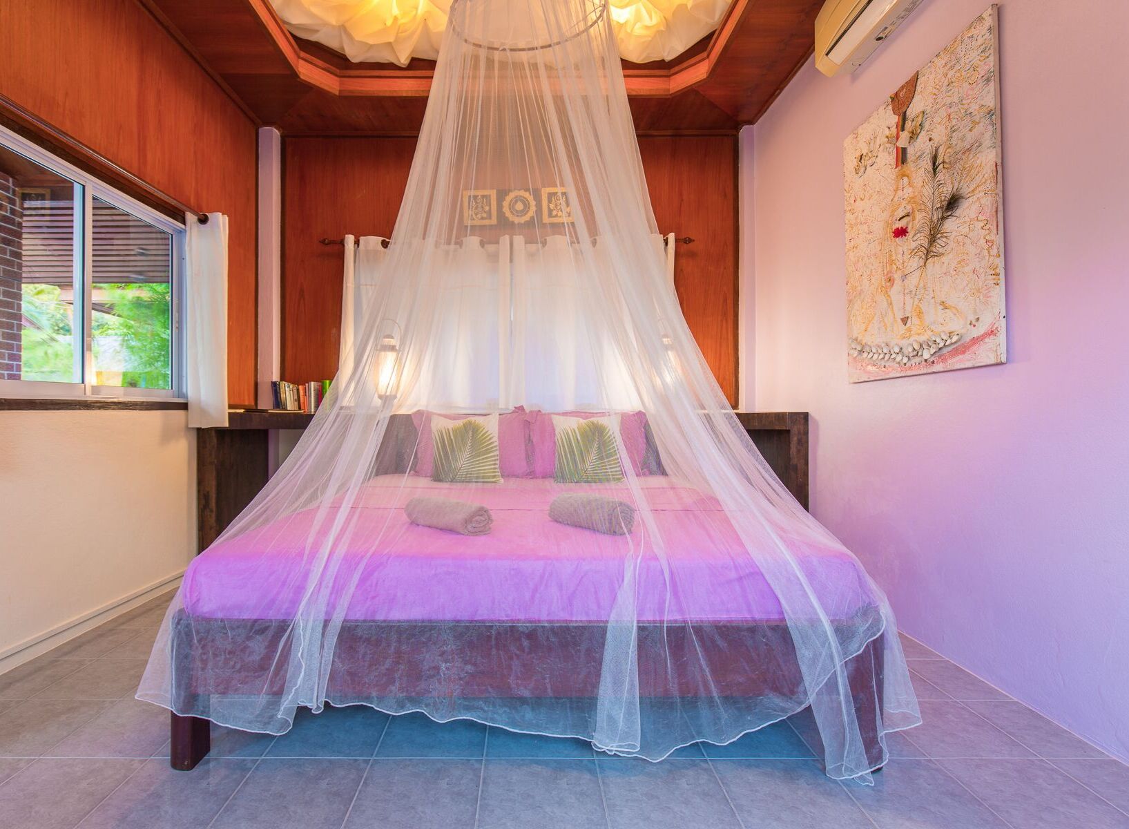 Une chambre à coucher avec un lit à baldaquin, une fenêtre avec des stores, une œuvre d’art accrochée au mur et un plafond en bois.
