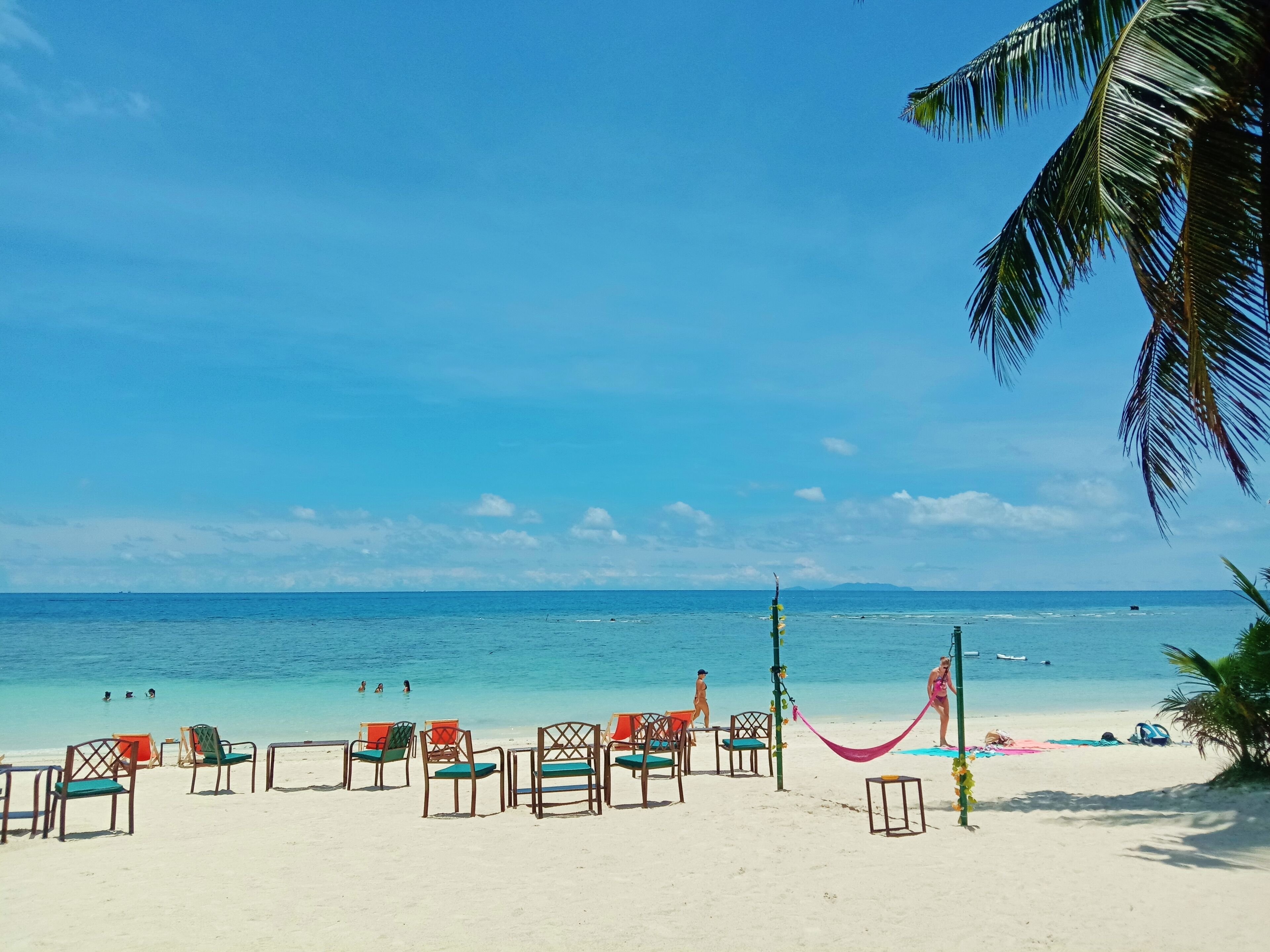 A beach with rows of colorful chairs and a hammock.