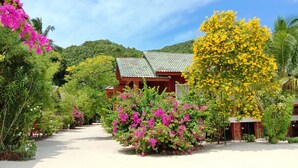 A traditional building with a tiled roof, surrounded by lush greenery and vibrant flowers. - Seaboard Bungalows (Ko Pha-ngan)