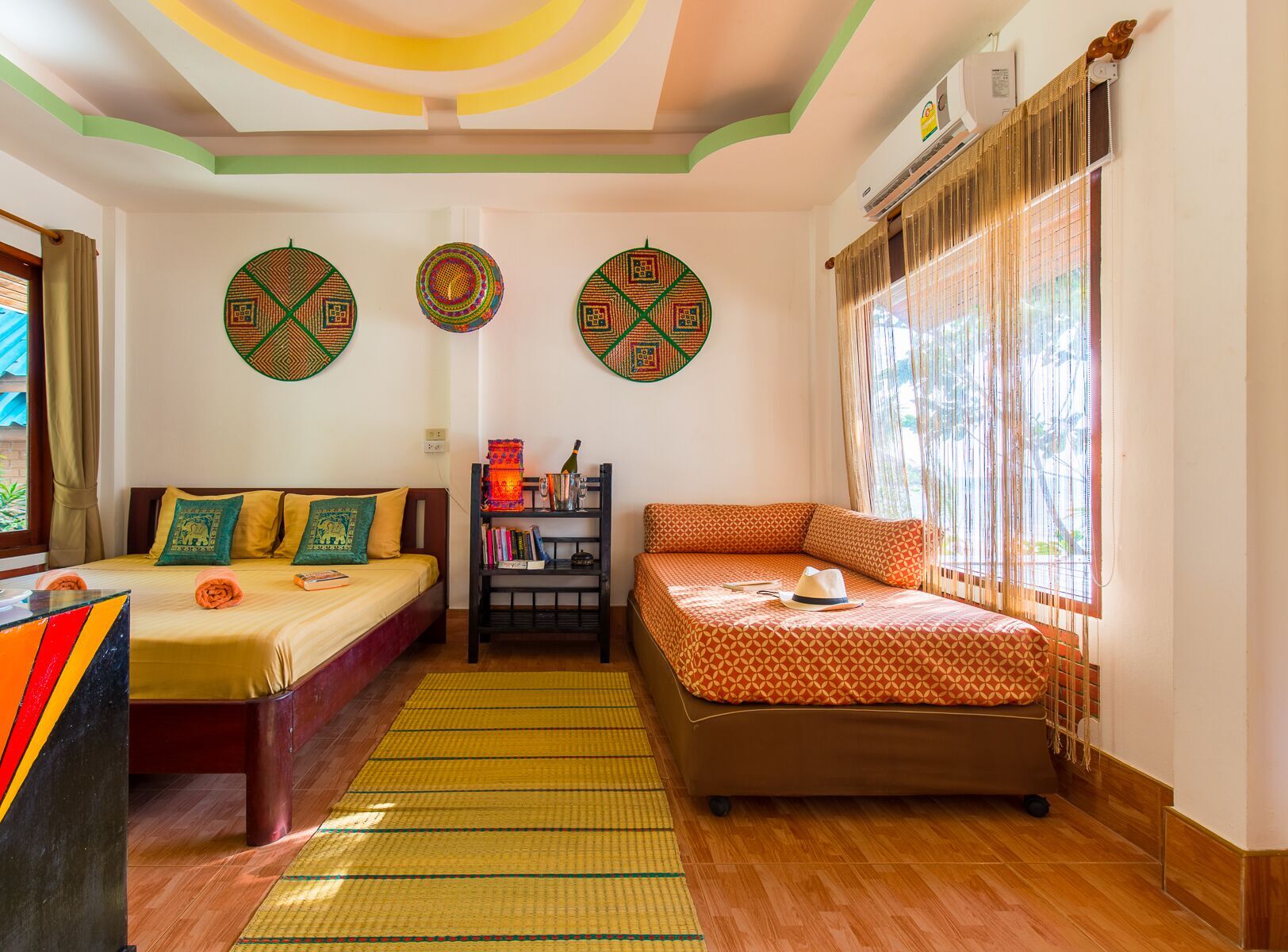 Una habitación con dos camas, una estantería con libros y decoración de pared.