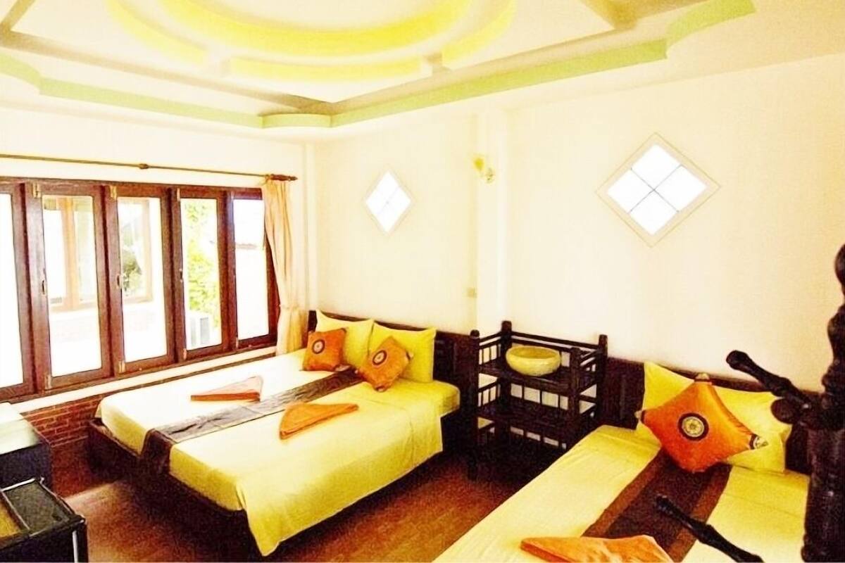 A room with two single beds, a wooden bench, and a small table.