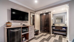 Une salle de bain moderne avec un grand miroir, des meubles en bois foncé, un lavabo intégré et un téléviseur à écran plat.