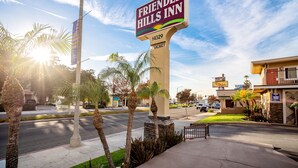 Une enseigne indiquant l’emplacement de l’hôtel Friendly Hills Inn, offrant une vue dégagée sur le parking et les bâtiments environnants.