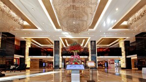A spacious lobby with a large chandelier, a central floral arrangement, and a digital information kiosk. - Haiyun Jin Jiang Internatonal Hotel (Shenyang)