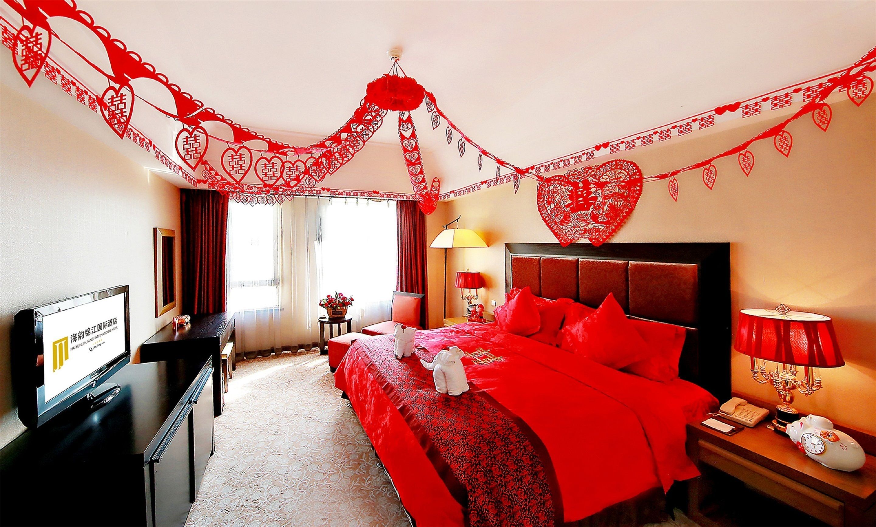 Una habitación de hotel con una cama grande, un escritorio con computadora, una lámpara y un teléfono.