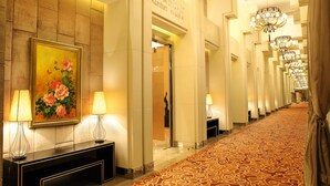 A hotel corridor with a patterned carpet, chandeliers, and a painting on the wall. - Haiyun Jin Jiang Internatonal Hotel (Shenyang)