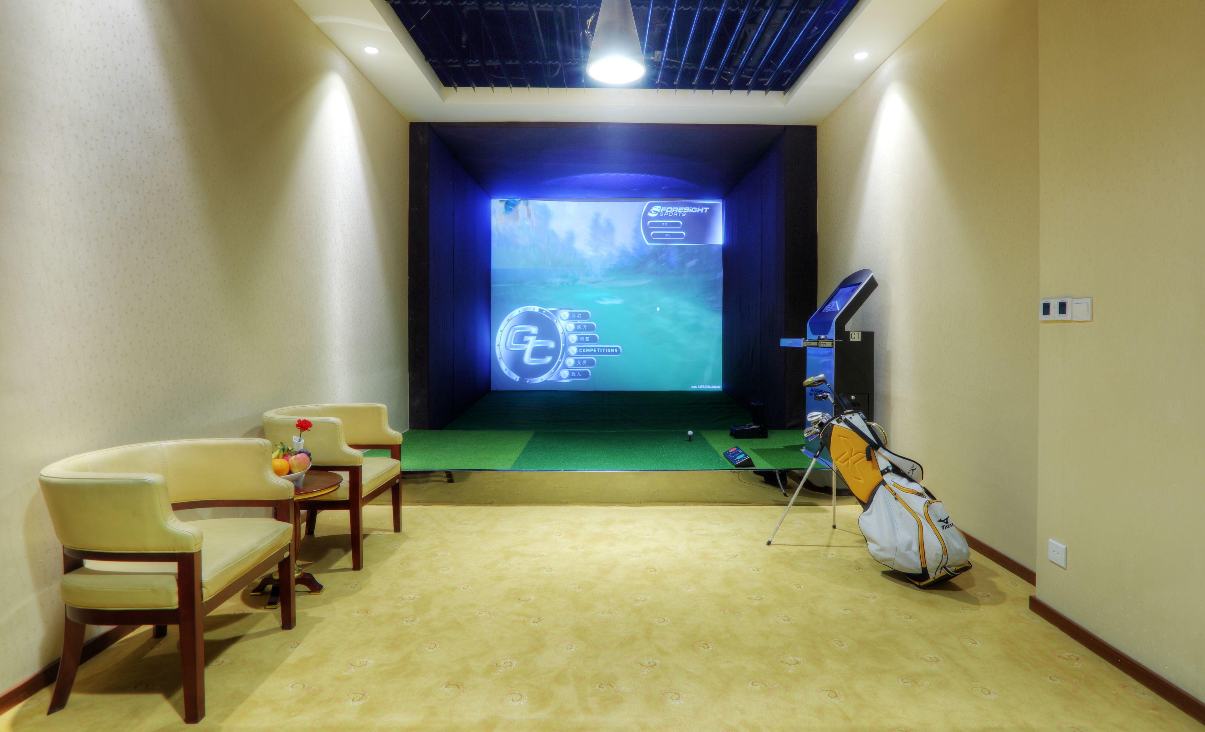 Une pièce équipée d’un écran de projection affichant l’interface d’un jeu de golf, d’un sac de golf et de deux chaises.